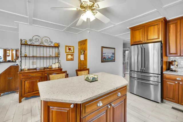 a kitchen with stainless steel appliances granite countertop a refrigerator a stove a sink a dining table and chairs with wooden floor