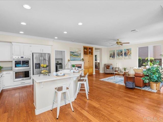 a kitchen with stainless steel appliances granite countertop a stove top oven a sink dishwasher and a refrigerator with wooden floor