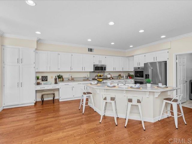 a kitchen with stainless steel appliances granite countertop a stove top oven a refrigerator a sink and a dining table with wooden floor