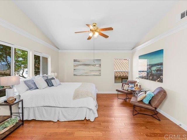 a bedroom with a large bed a chandelier and a painting on the wall
