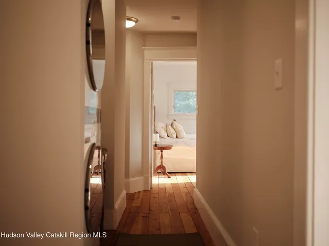 a view of a hallway with wooden floor and a bathroom