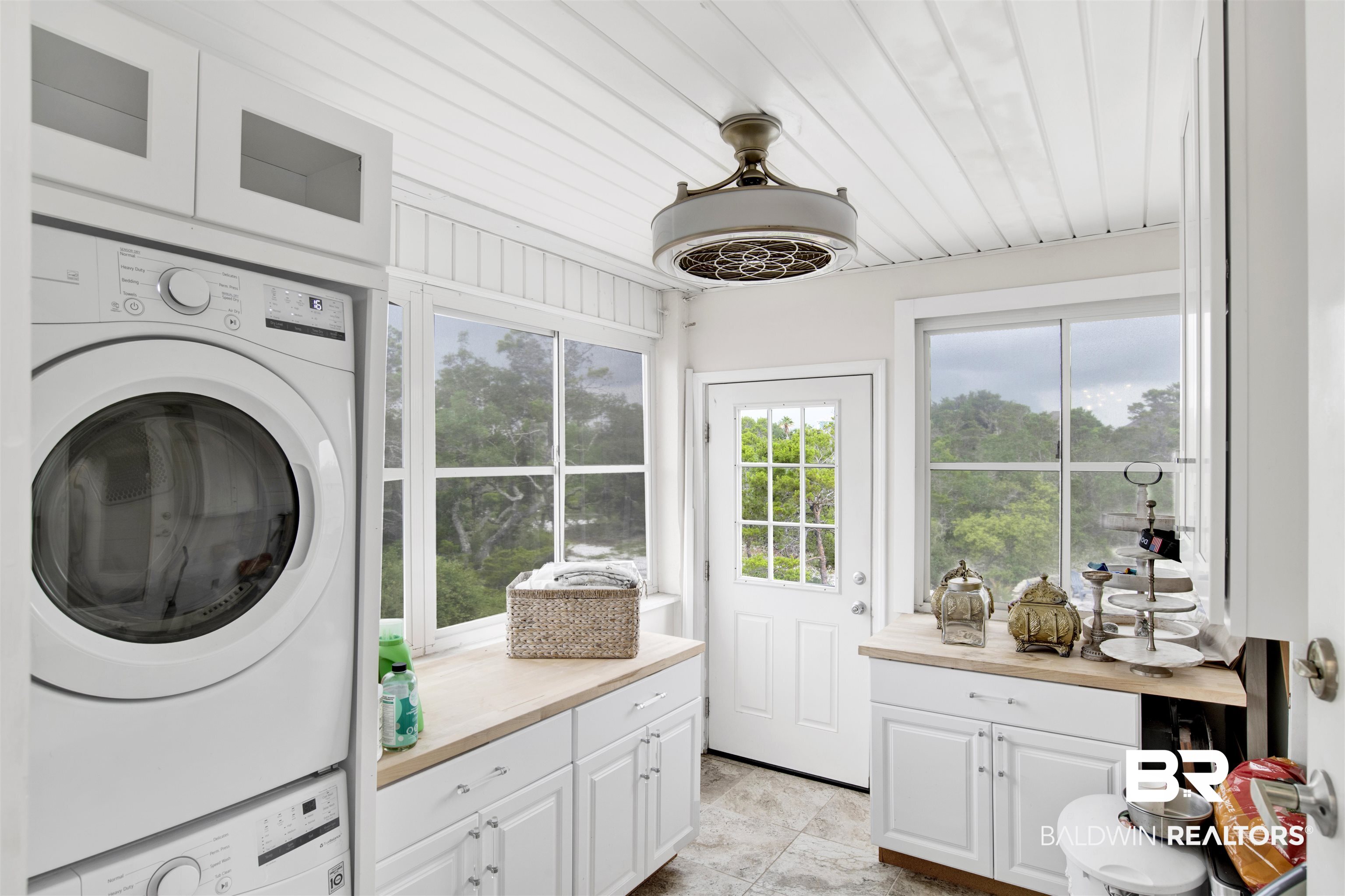 30351 River Road Orange Beach, AL 36561 - Photo 32 of 44 Laundry room with a stacked washer and dryer, white cabinetry, wood-finish countertops, and a white paneled ceiling