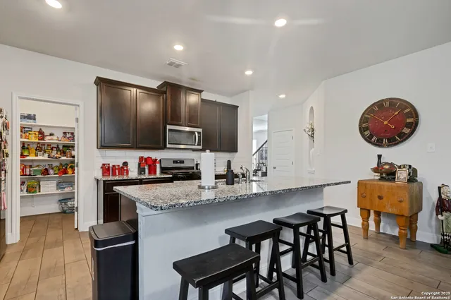 a kitchen with stainless steel appliances granite countertop a table and chairs in it