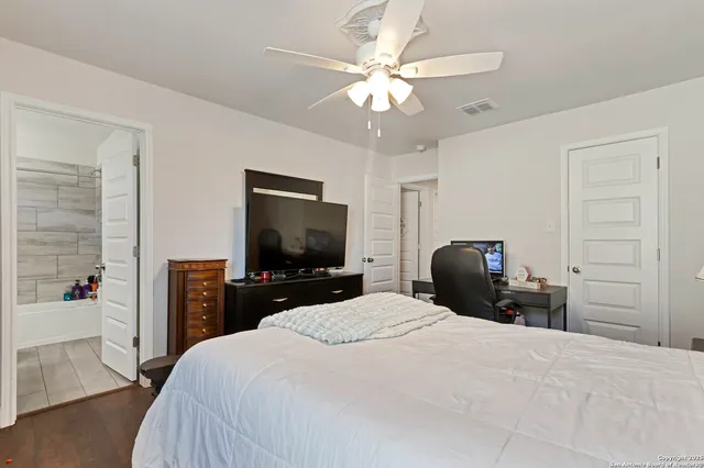 a bedroom with a bed a chandelier and a flat tv screen on dresser