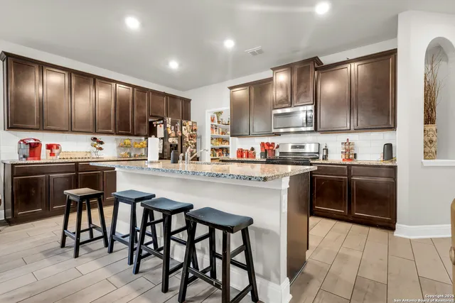 a kitchen with kitchen island granite countertop wooden cabinets and white appliances