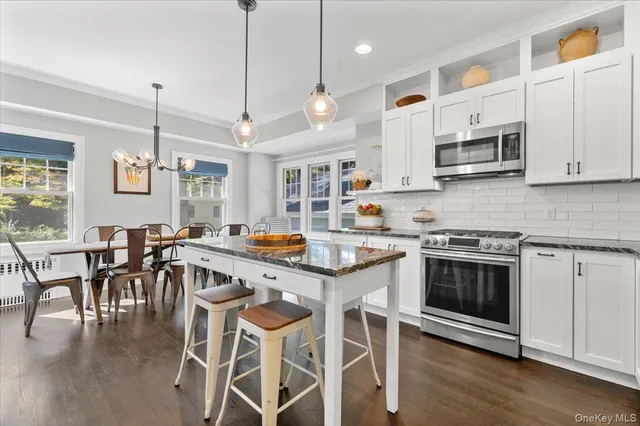 a kitchen with stainless steel appliances granite countertop a stove a sink a dining table and chairs with wooden floor