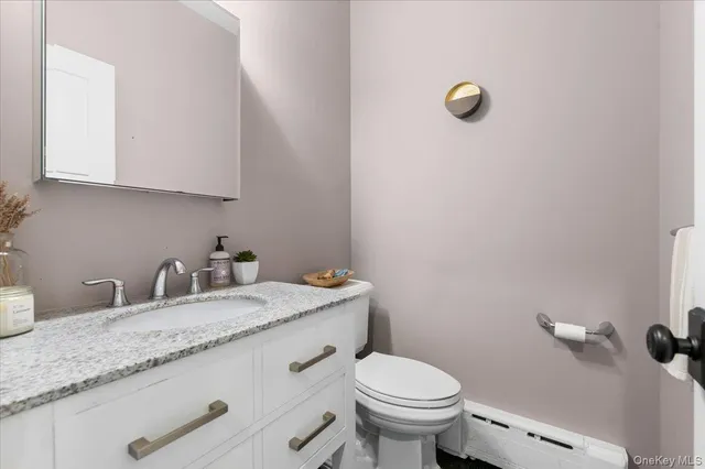 a bathroom with a granite countertop sink and a toilet