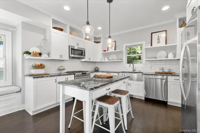 a kitchen with granite countertop white cabinets and stainless steel appliances