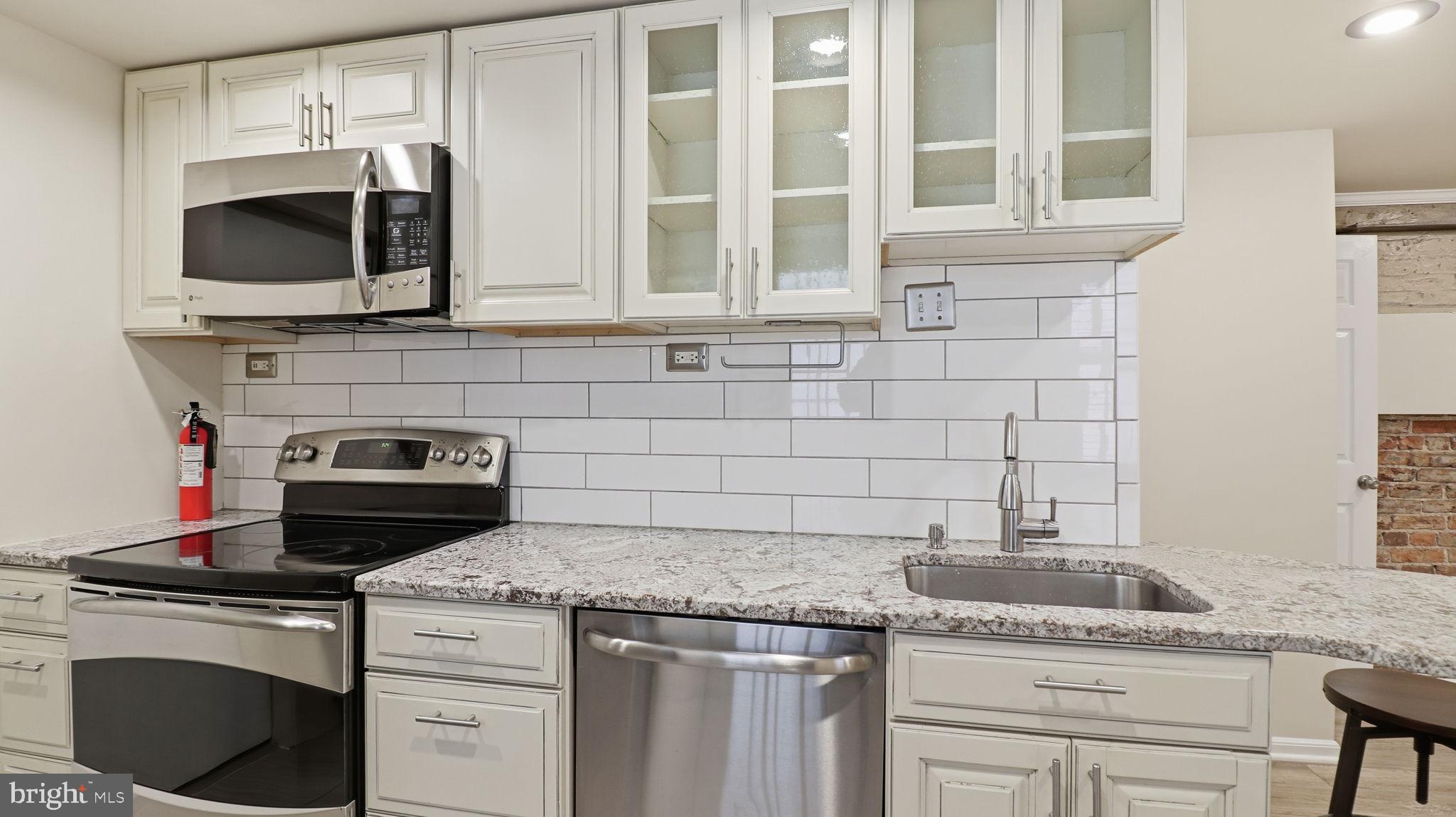 1450 Harvard Street Northwest, Unit B Washington, DC 20009 - Photo 12 of 35 a kitchen with stainless steel appliances granite countertop a stove and a microwave
