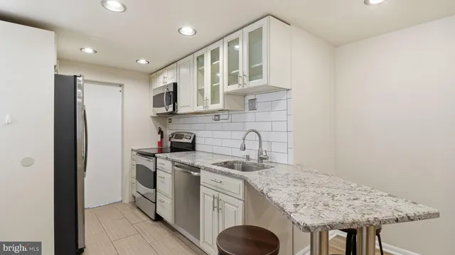 a kitchen with stainless steel appliances granite countertop a sink a stove and a refrigerator