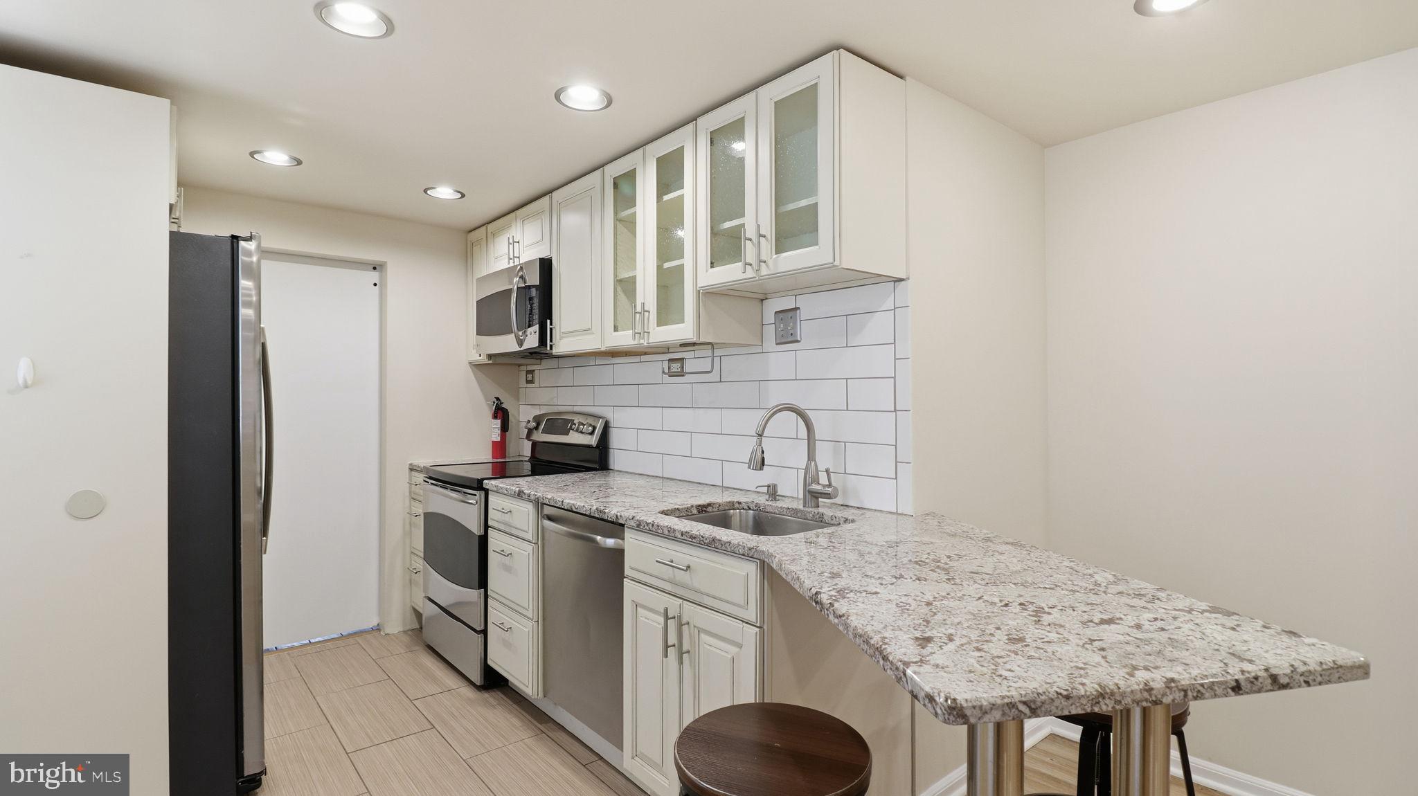 1450 Harvard Street Northwest, Unit B Washington, DC 20009 - Photo 13 of 35 a kitchen with stainless steel appliances granite countertop a sink a stove and a refrigerator