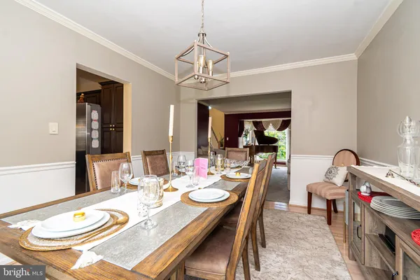 a dining room with wooden floor a chandelier a wooden table and chairs