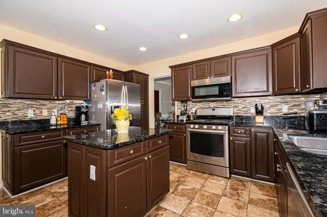 a kitchen with granite countertop a stove top oven microwave and cabinets