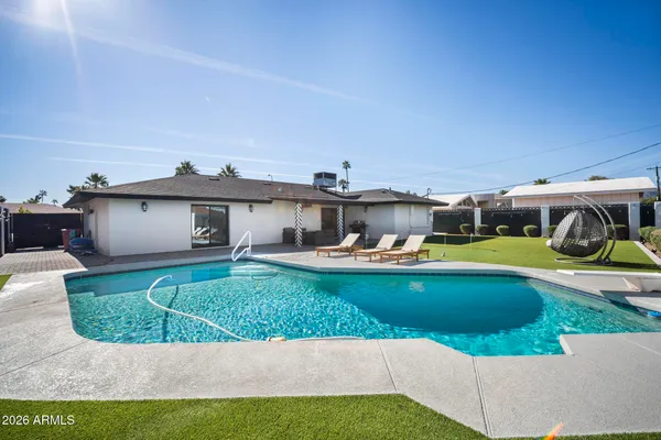 a view of a white house with a yard patio and swimming pool