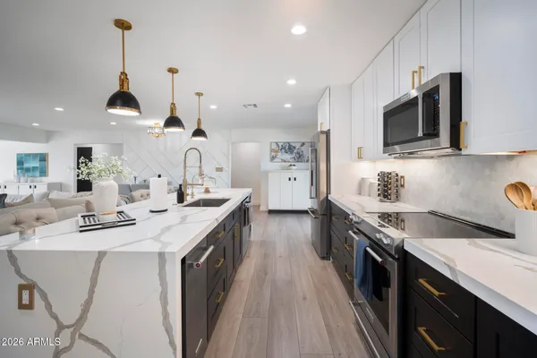 a kitchen with stainless steel appliances granite countertop a sink a stove and a wooden floors