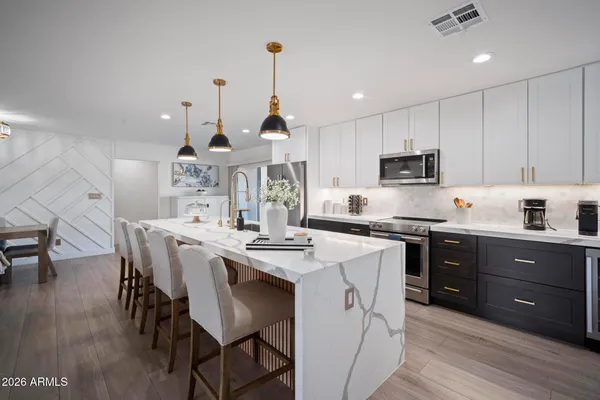 a kitchen with stainless steel appliances kitchen island granite countertop a stove a sink a dining table and chairs