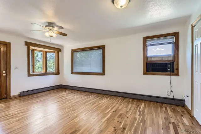 a view of an empty room with a window and wooden floor