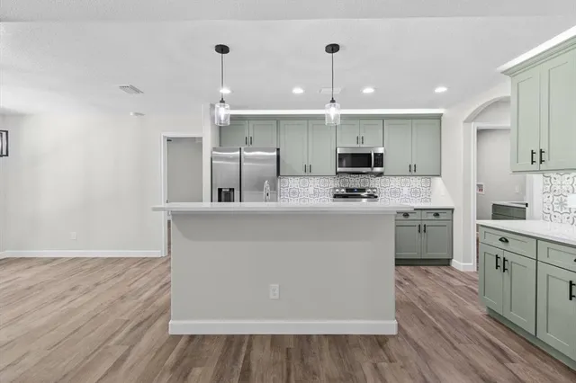 a kitchen with kitchen island granite countertop a sink stainless steel appliances and white cabinets