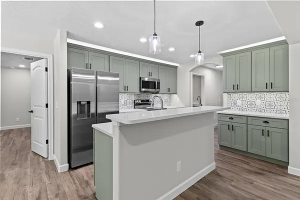 a kitchen with kitchen island a sink stainless steel appliances and refrigerator