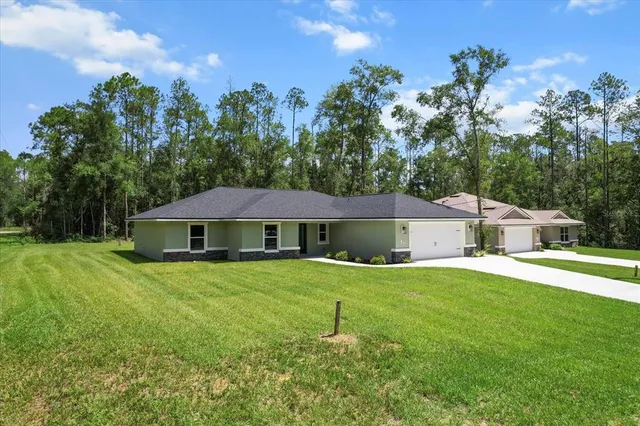 a view of a house with a yard and large trees