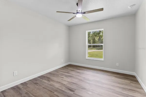 an empty room with wooden floor closet and fan
