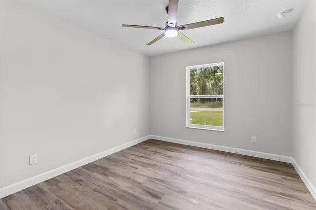 an empty room with wooden floor closet and fan