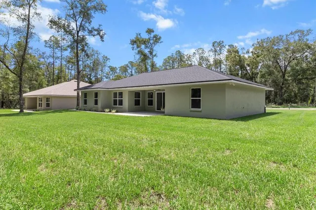 an aerial view of a house with a yard and trees all around