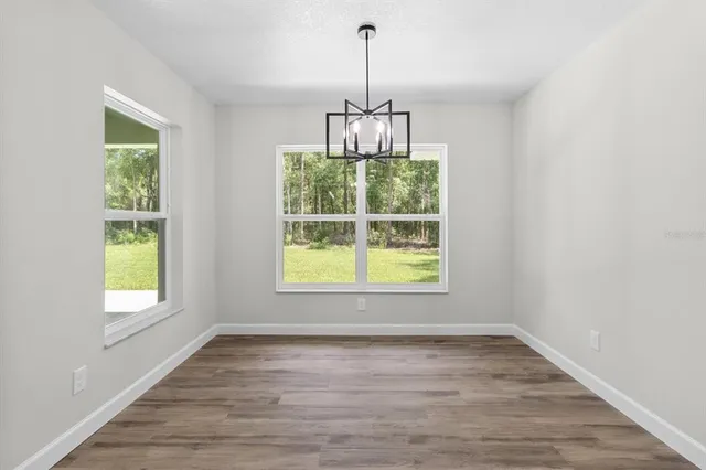an empty room with wooden floor a chandelier and windows