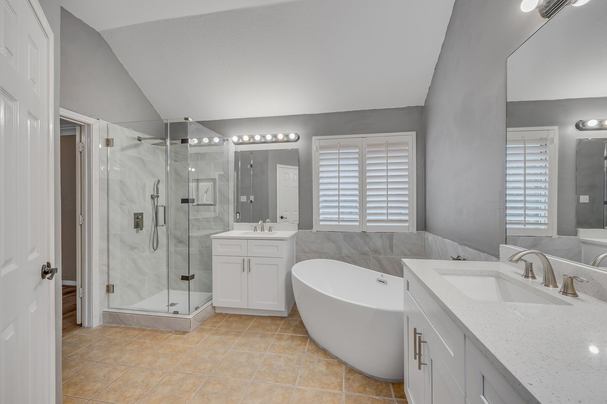 2726 Grimes Ranch Road Austin, TX 78732 - Photo 27 of 35 Bathroom featuring lofted ceiling, a freestanding tub, two vanities, a marble finish shower, and tile walls