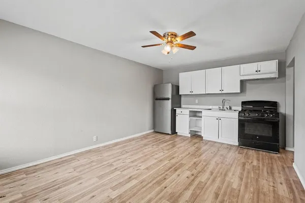 a kitchen with a stove a refrigerator and white cabinets