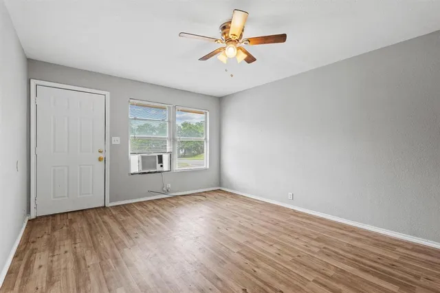 a view of an empty room with window and a kitchen