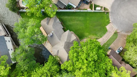 an aerial view of a house with a yard and trees all around