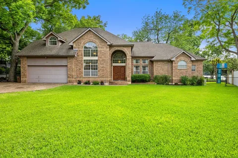 a view of a brick house with a big yard and large trees