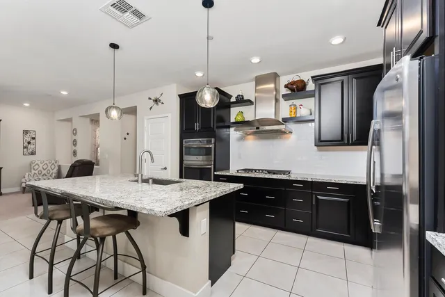 a kitchen with stainless steel appliances kitchen island granite countertop a refrigerator a sink and a stove