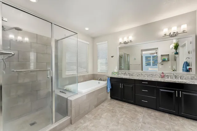 a bathroom with a tub a double vanity sink and mirror