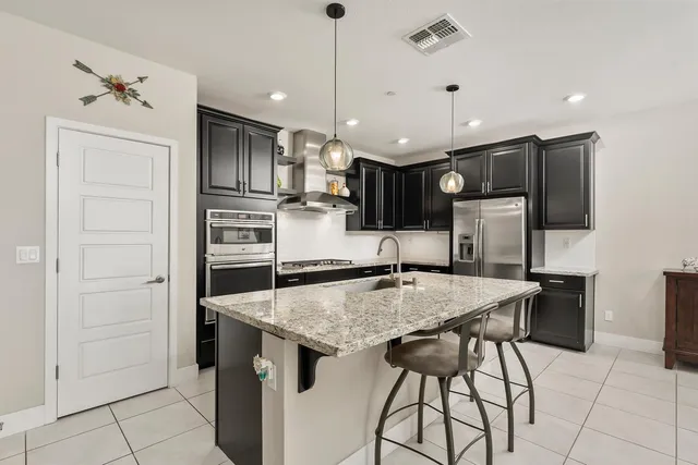 a kitchen with stainless steel appliances granite countertop a sink refrigerator and chairs