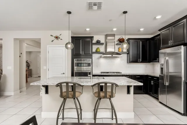 a kitchen with stainless steel appliances kitchen island granite countertop a stove a sink and a refrigerator