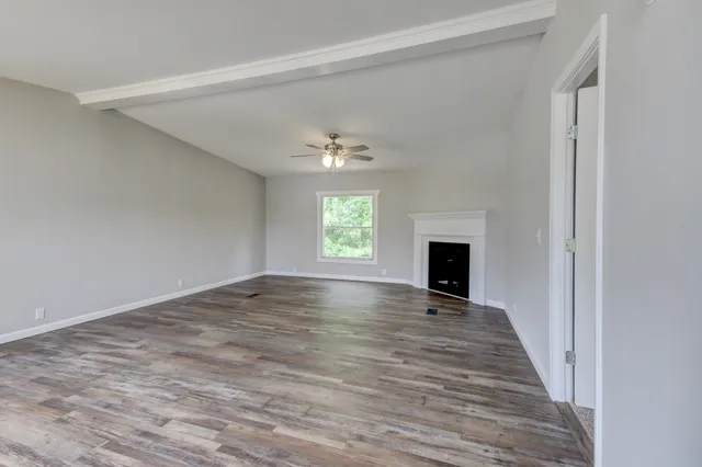 a view of an empty room with window and wooden floor