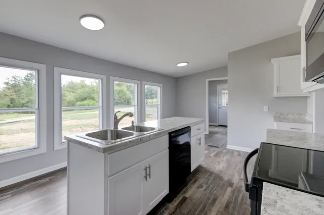 a kitchen with granite countertop a sink and a stove top oven