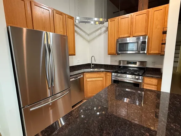 a kitchen with granite countertop a refrigerator and a stove top oven
