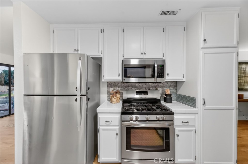 32042 Merlot Court Temecula, CA 92591 - Photo 18 of 46 a kitchen with a refrigerator a stove and white cabinets