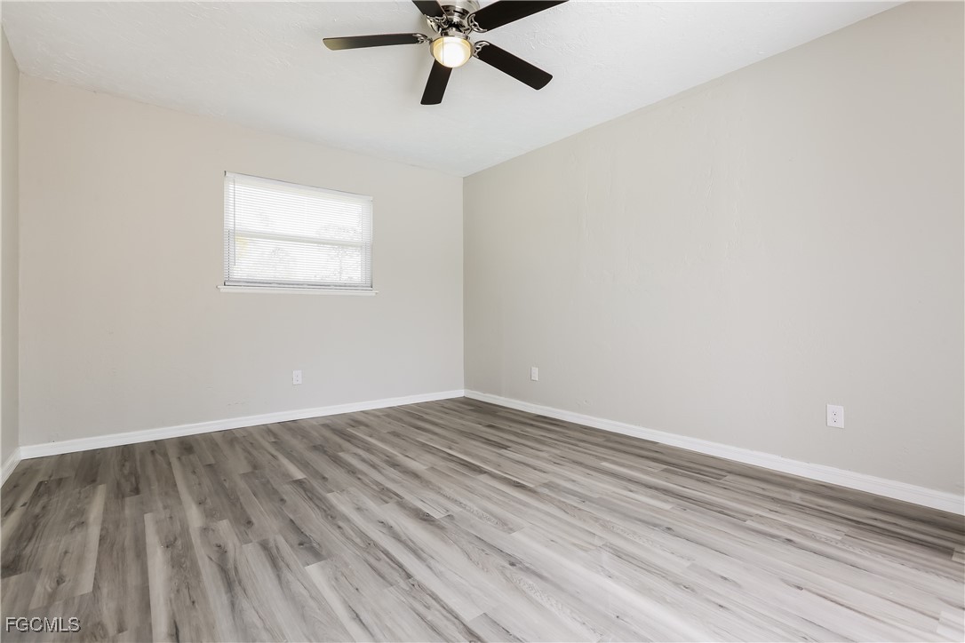 4007 Allure Lane North Port, FL 34287 - Photo 6 of 16 a view of an empty room with wooden floor and a ceiling fan