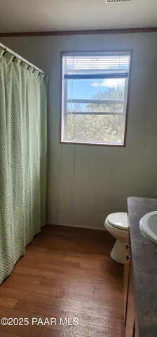 a view of an empty room with wooden floor and closet