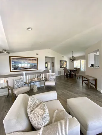 a living room with couches and kitchen view with wooden floor