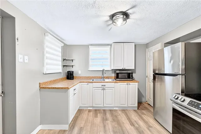 a kitchen with a sink a refrigerator a stove and white cabinets