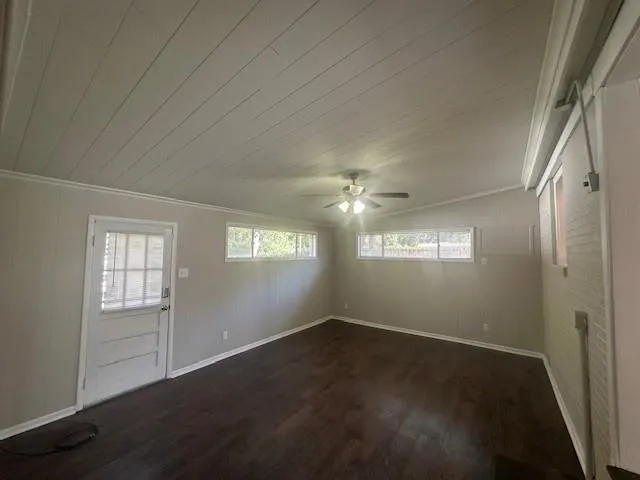 an empty room with wooden floor closet and windows