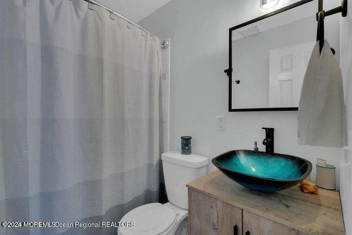 3125 Creek Road Toms River, NJ 08753 - Photo 16 of 60 a bathroom with a toilet a sink and mirror