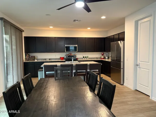 a kitchen with stainless steel appliances a stove a refrigerator a sink a dining table and chairs