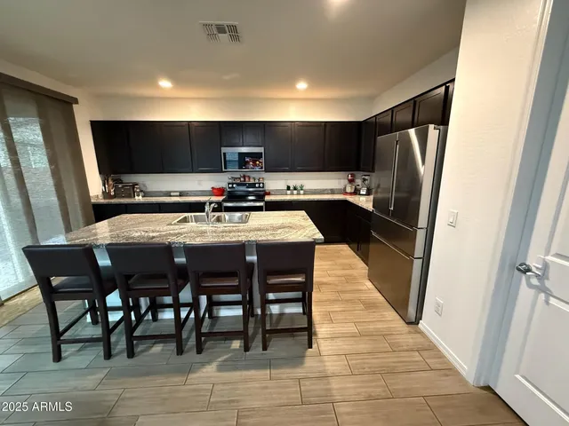 a kitchen with stainless steel appliances a table chairs refrigerator and a sink
