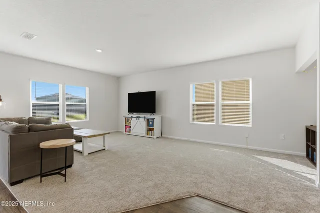a living room with furniture a flat screen tv and a window